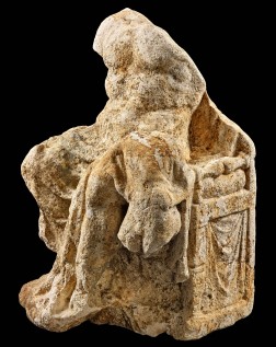 Skulpturfragment aus hellem Stein mit unbekleidetem Männerkörper