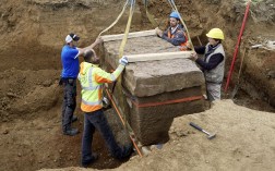 Vier Arbeiter sichern den römischen Sarkophag, der durch den Bagger gehoben wird