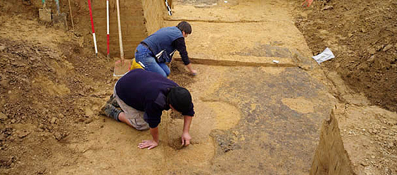 Befundbearbeitung in einem mittelalterlichen Keller. Am Boden sind die Standspuren von Gefäßen zu erkennen. Foto: Archaeonet